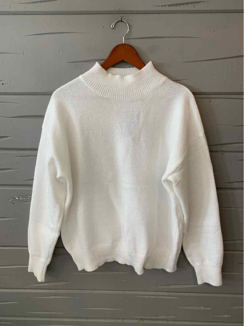 White long-sleeve crewneck sweater with a soft knit texture and ribbed cuffs and hem, hanging on a wooden hanger.