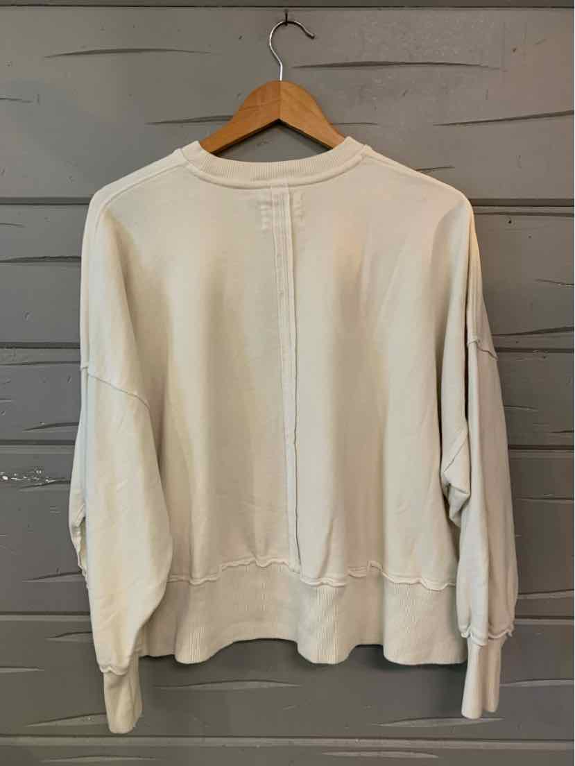 Cream-colored long sleeve crewneck sweatshirt with ribbed cuffs and hem, relaxed fit.