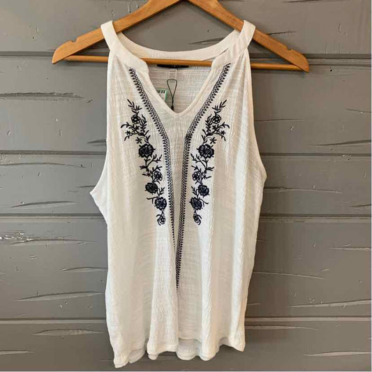 White sleeveless tank top with black floral embroidery and scoop neckline on wooden hanger.