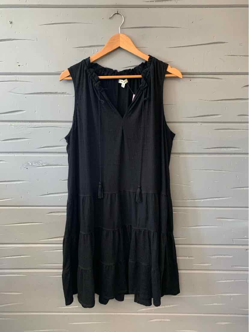 Black sleeveless tiered dress with v-neck and loose fit hanging on wooden hanger.