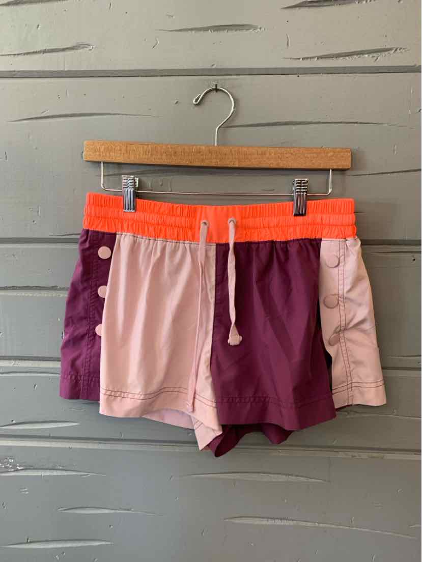 Color block women's athletic shorts with lilac, burgundy, and light pink panels, featuring an orange elastic waistband and.