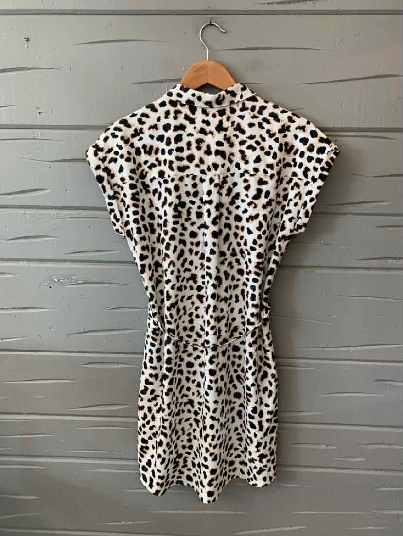 White knee-length dress with black and brown leopard spots, short sleeves, cinched waist, and round neckline.