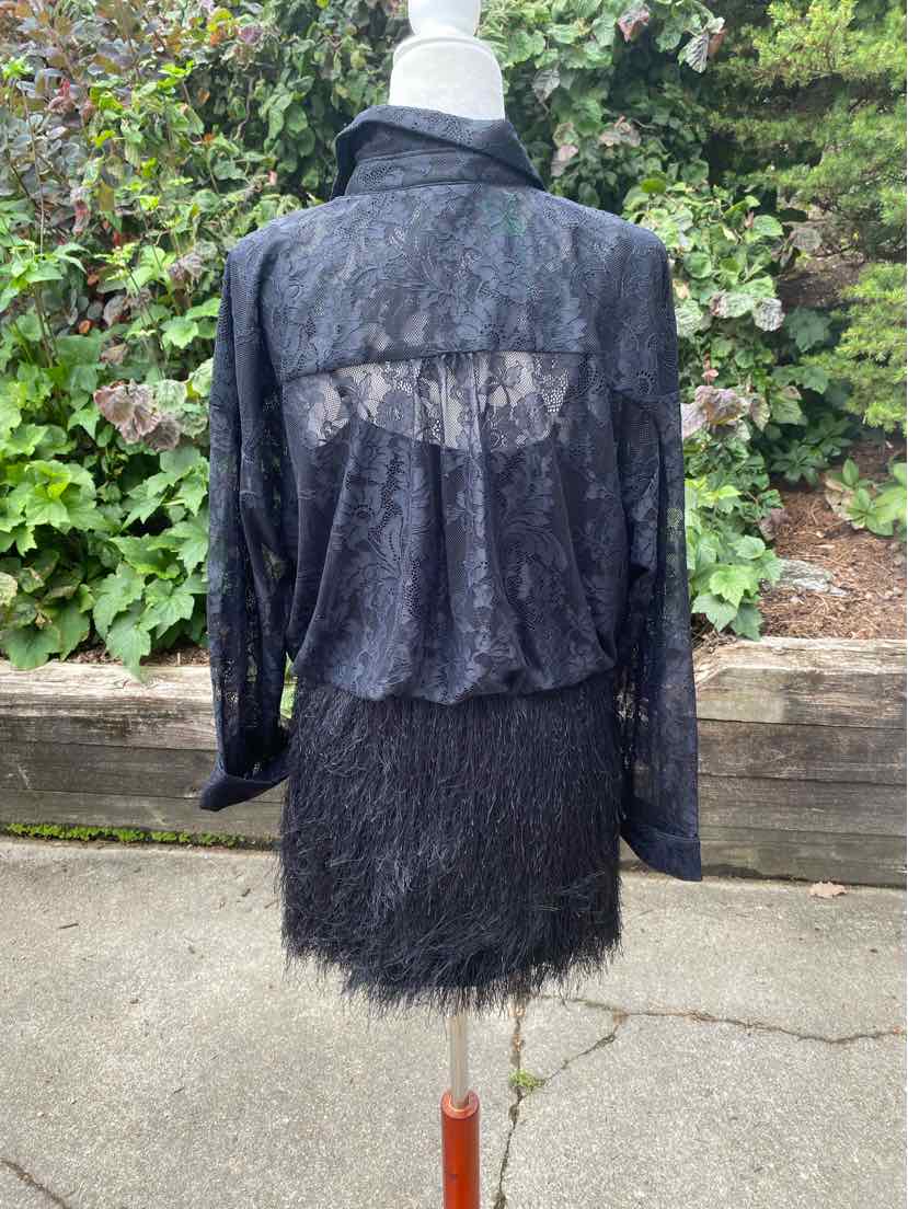 Black lace long-sleeve top with sheer back panel paired with a textured black skirt featuring fringe hem.