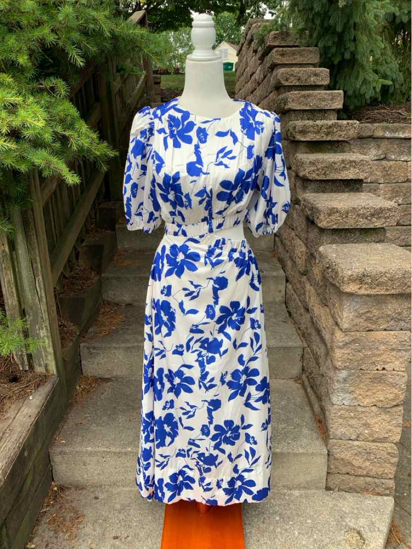 White midi dress with bold blue floral print, puffed short sleeves, and fitted waist.