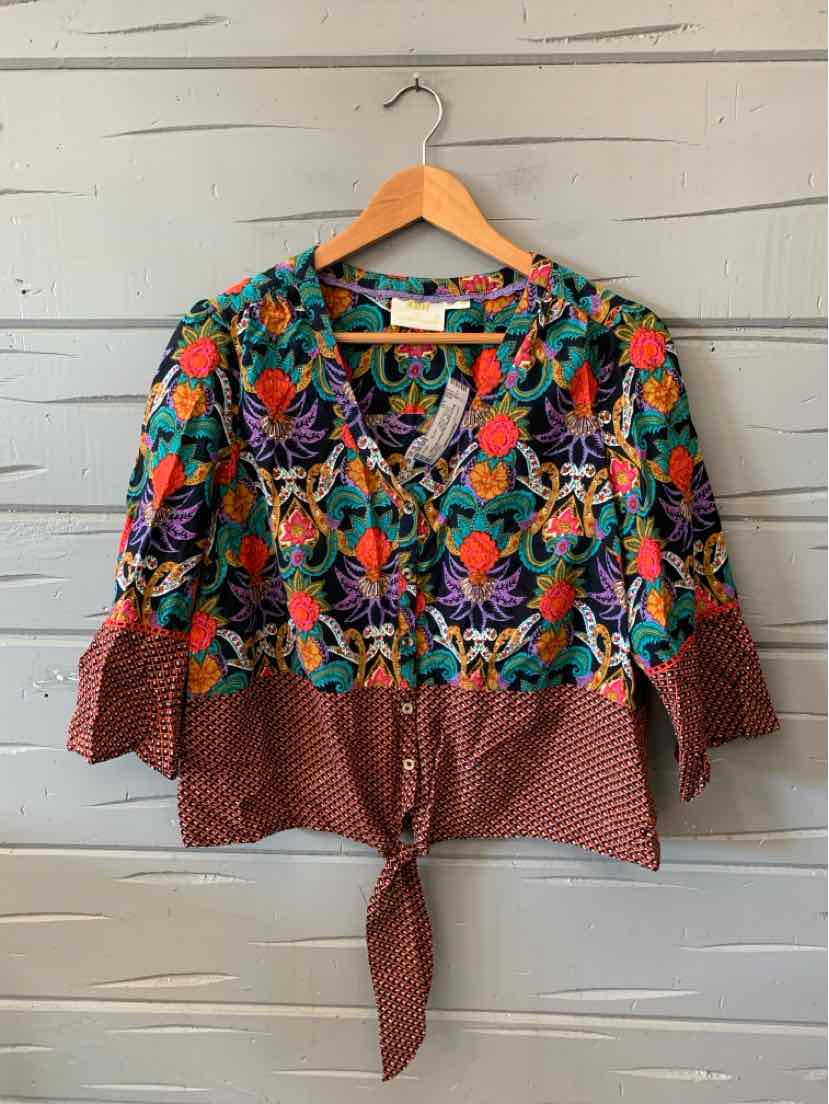 Women’s multicolor floral blouse with three-quarter sleeves, a V-neck, and a red patterned tie hem.