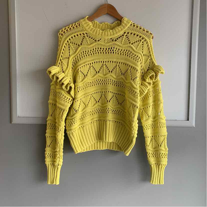 Yellow knitted sweater with ruffled shoulders and geometric openwork pattern.