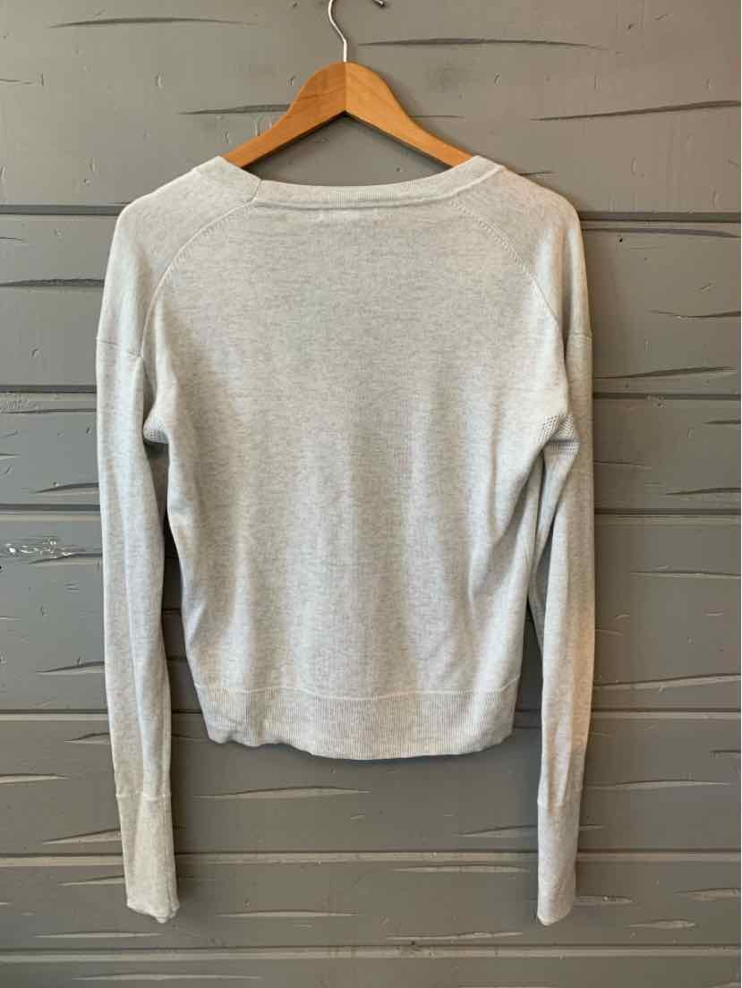 Light gray long-sleeve knit sweater with crew neckline and slim fit hanging on wooden hanger.