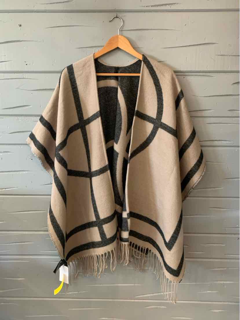 Beige woven shawl with black abstract grid pattern and fringe trim hanging on wooden hanger.