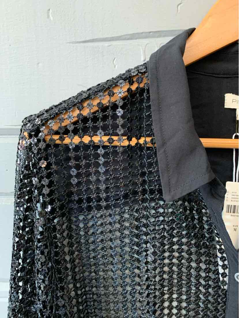 Black sequin-covered top with solid black collar on wooden hanger against white background.