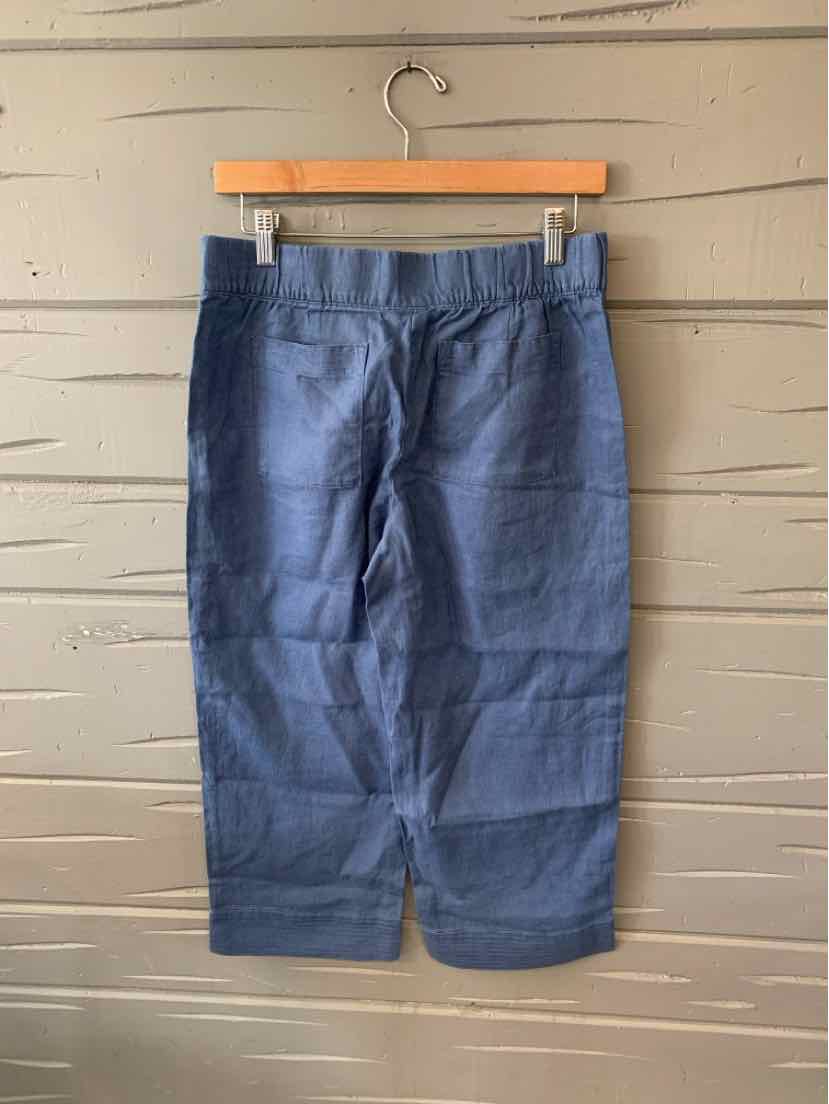 Blue linen cropped pants with a straight leg and front pockets hanging on wooden hanger.