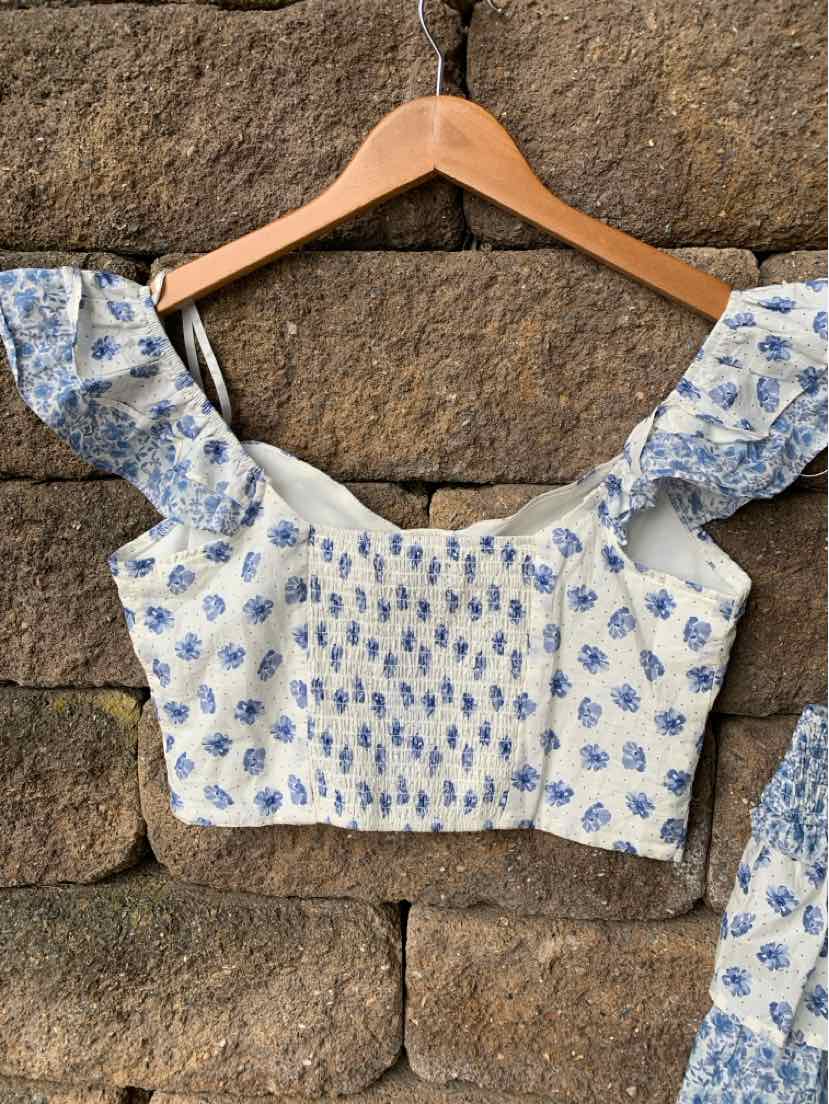 White crop top with blue paisley print, smocked bodice, and ruffled shoulder straps.