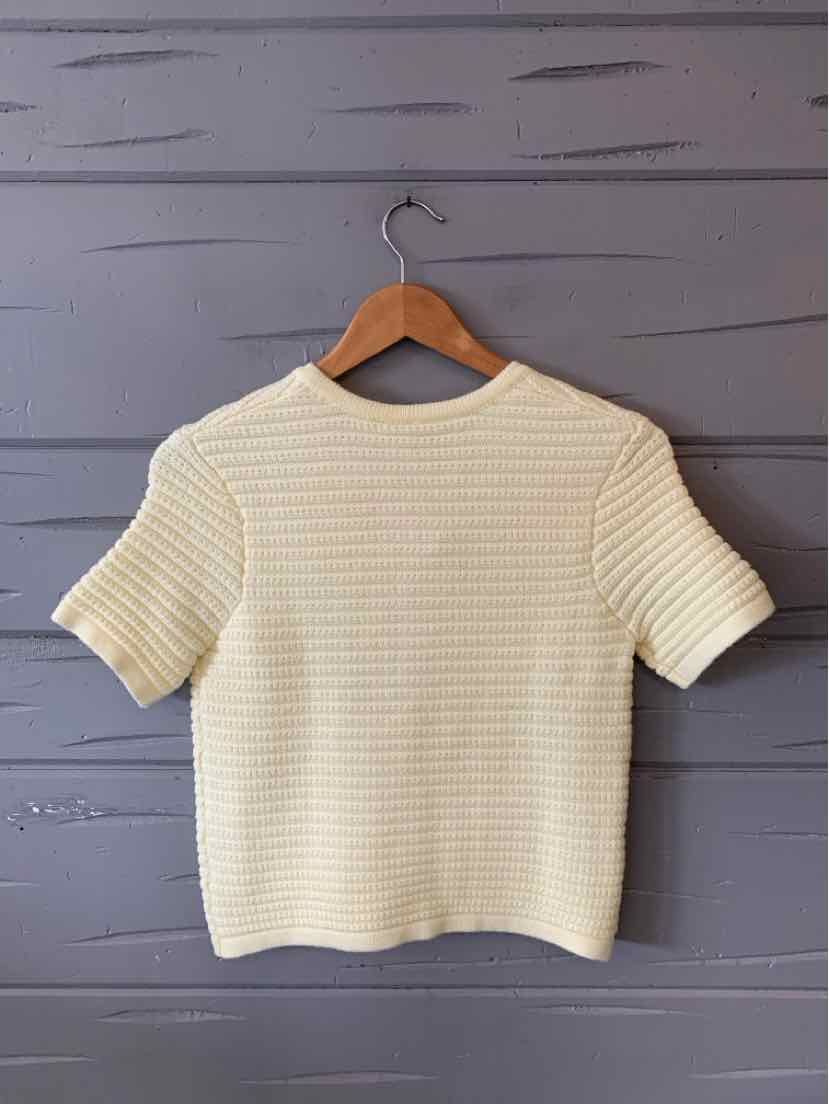 Cream-colored short-sleeve knit top with subtle horizontal ribbing, rounded neckline.
