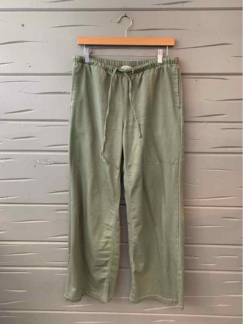 Light olive green drawstring casual pants with wide legs and side pockets hanging on wooden hanger.