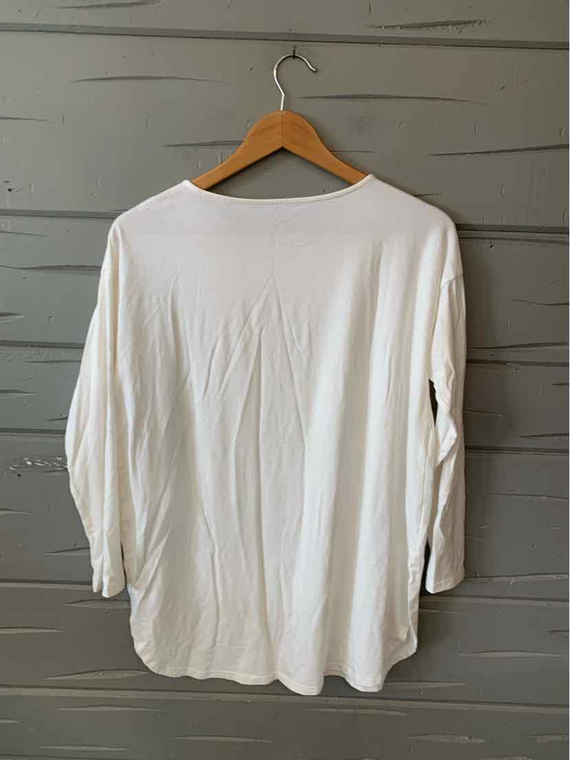 White long-sleeve shirt with relaxed fit, crew neckline, and soft fabric on wooden hanger.