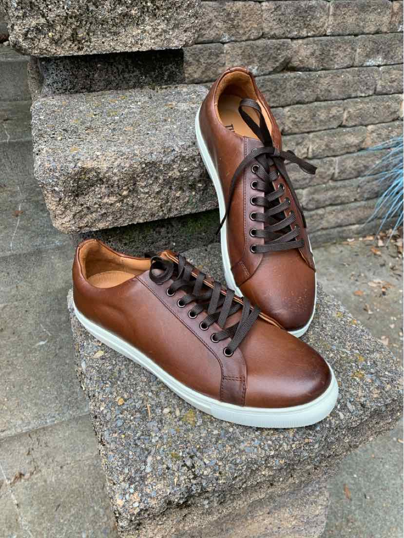Women’s brown leather lace up sneakers sitting on a cement block step