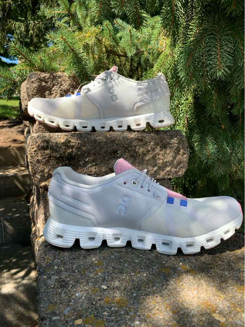 White athletic sneakers with segmented sole cushions, lace-up closure, and subtle logo accents, size 9.
