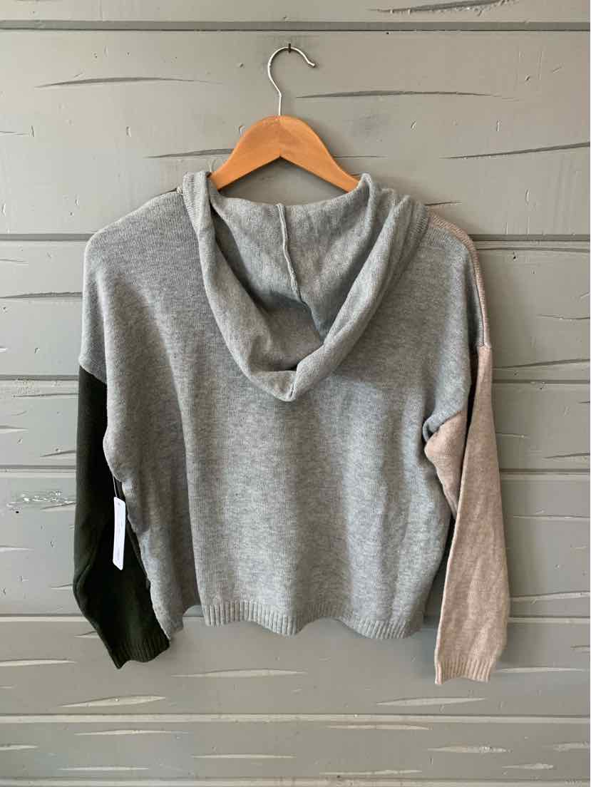 Color block hoodie with grey body, black left sleeve, beige right sleeve, and relaxed fit on wooden hanger.