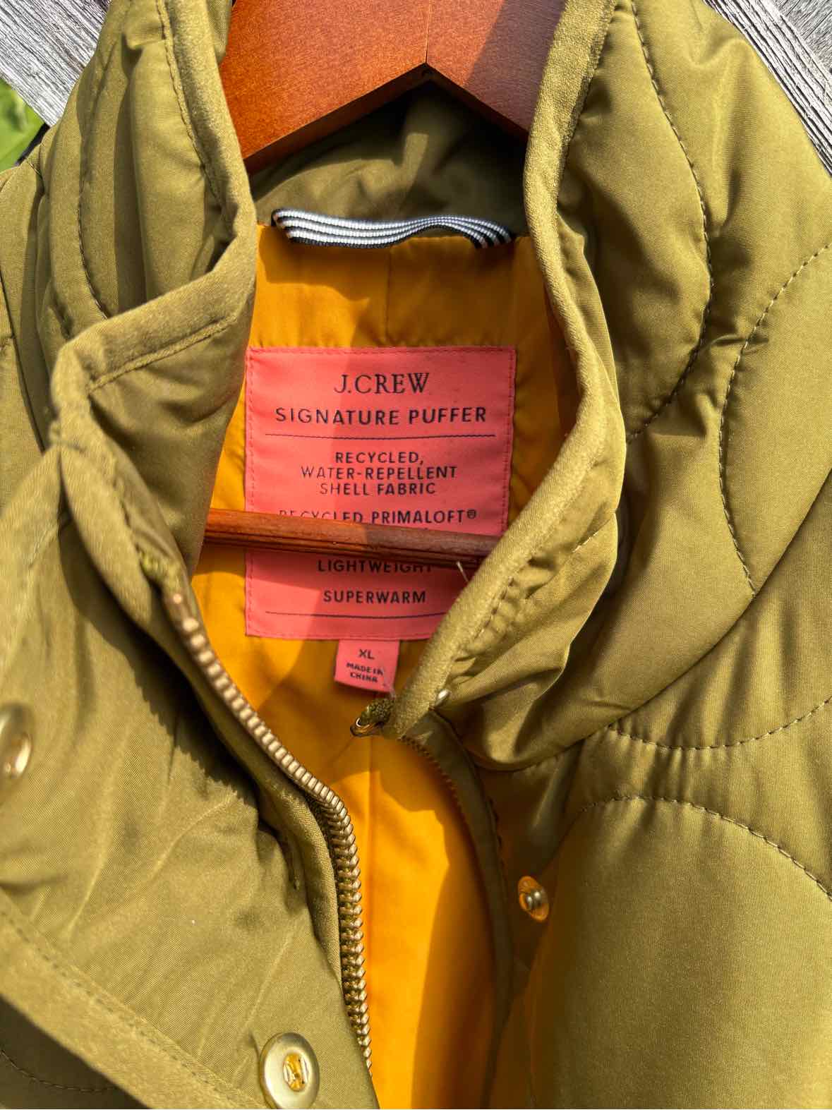 Olive green J.Crew jacket with a quilted collar, brass snaps, zipper, and orange lining.