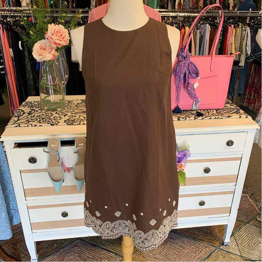 Brown sleeveless dress with embroidered white floral hem on a mannequin.