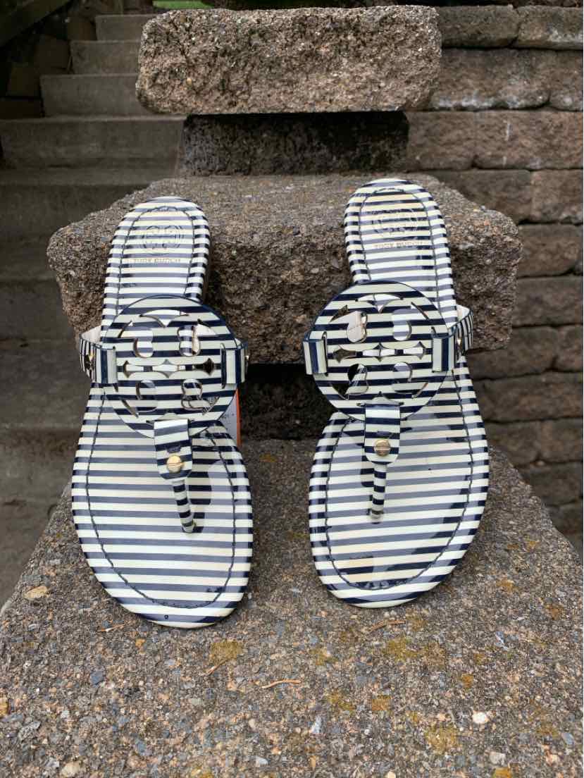 Women's Tory Burch size 7.5 flat sandals with black and white stripes and a large interlocking logo buckle on the straps.