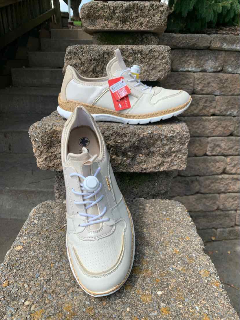 Beige and white sneaker with mesh and suede panels, white laces, and a cushioned sole.