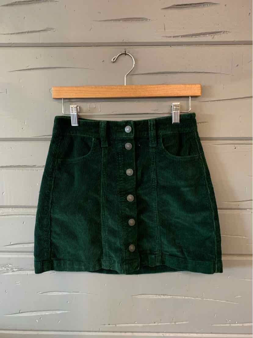 Dark green corduroy skirt with front button closure and two front pockets, mini length.
