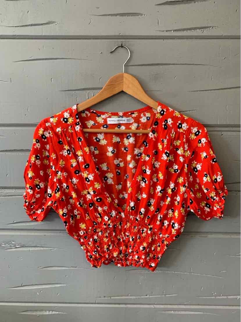 Red cropped blouse with white and blue floral print, puffed short sleeves, and elastic waist.