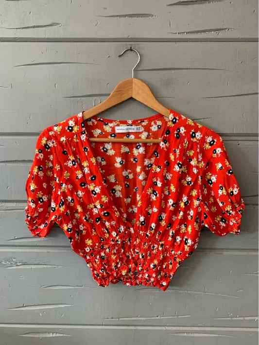 Red cropped blouse with white and blue floral print, puffed short sleeves, and elastic waist.