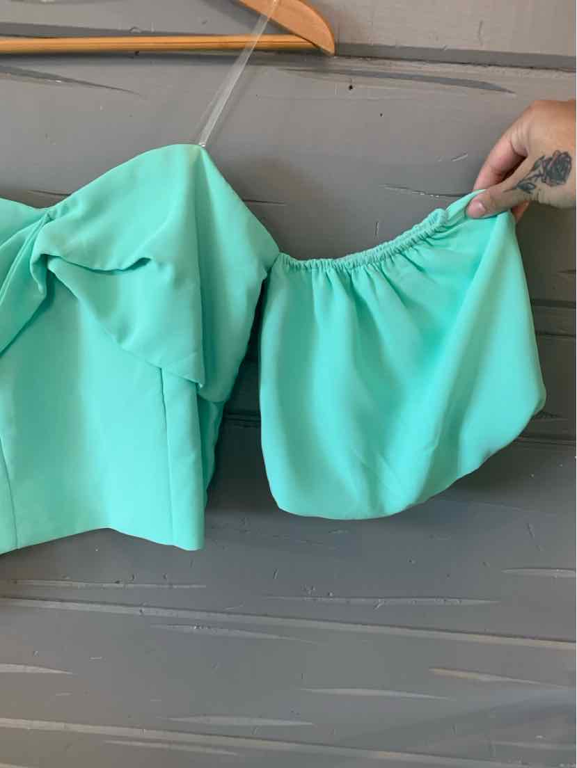 Mint green off-shoulder top with puff sleeves and square neckline hanging on wooden hanger.