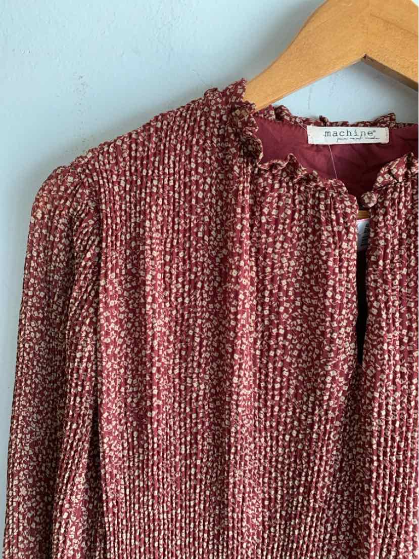 Burgundy textured knit sweater with ruffled collar and button closure on wooden hanger.