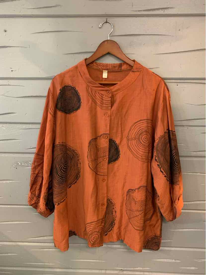Orange long-sleeve blouse with large abstract circular patterns and a round neckline with a small front slit.