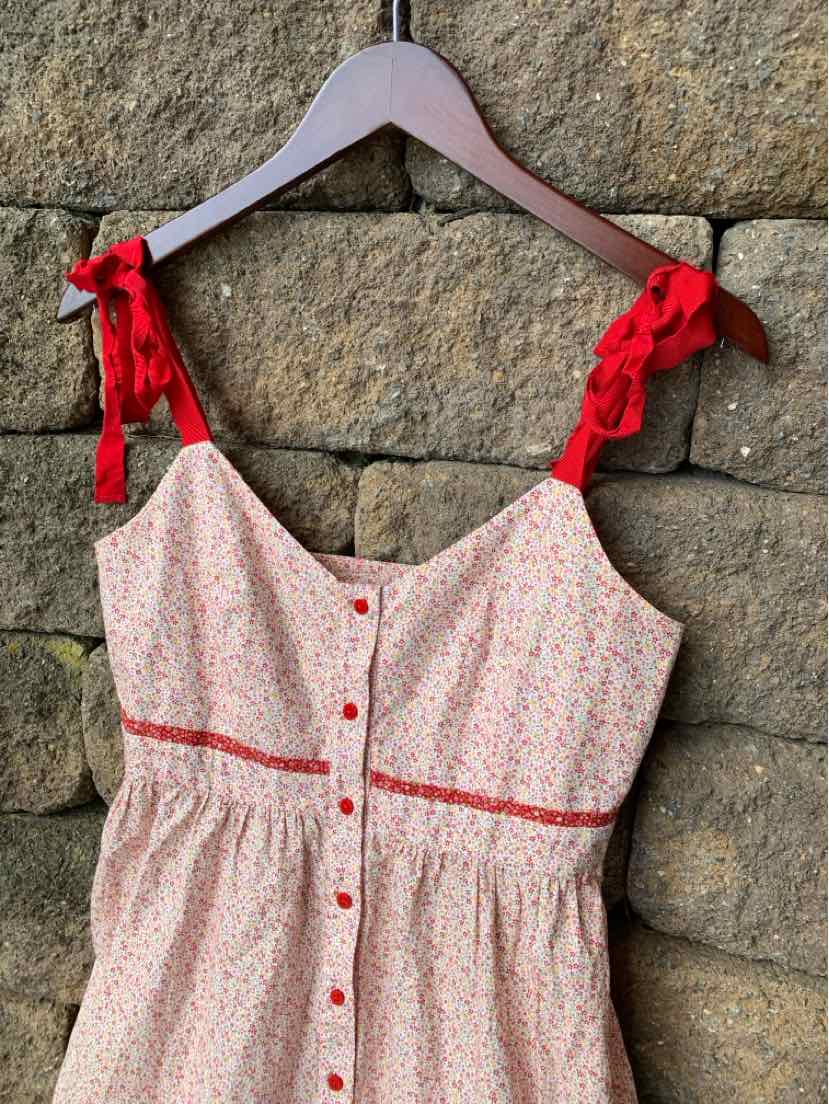 Red and white floral sleeveless dress with button front and tied shoulder straps.
