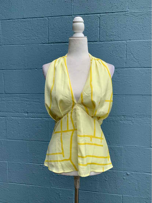 Sleeveless yellow halter top with abstract white patchwork pattern and deep V-neckline.