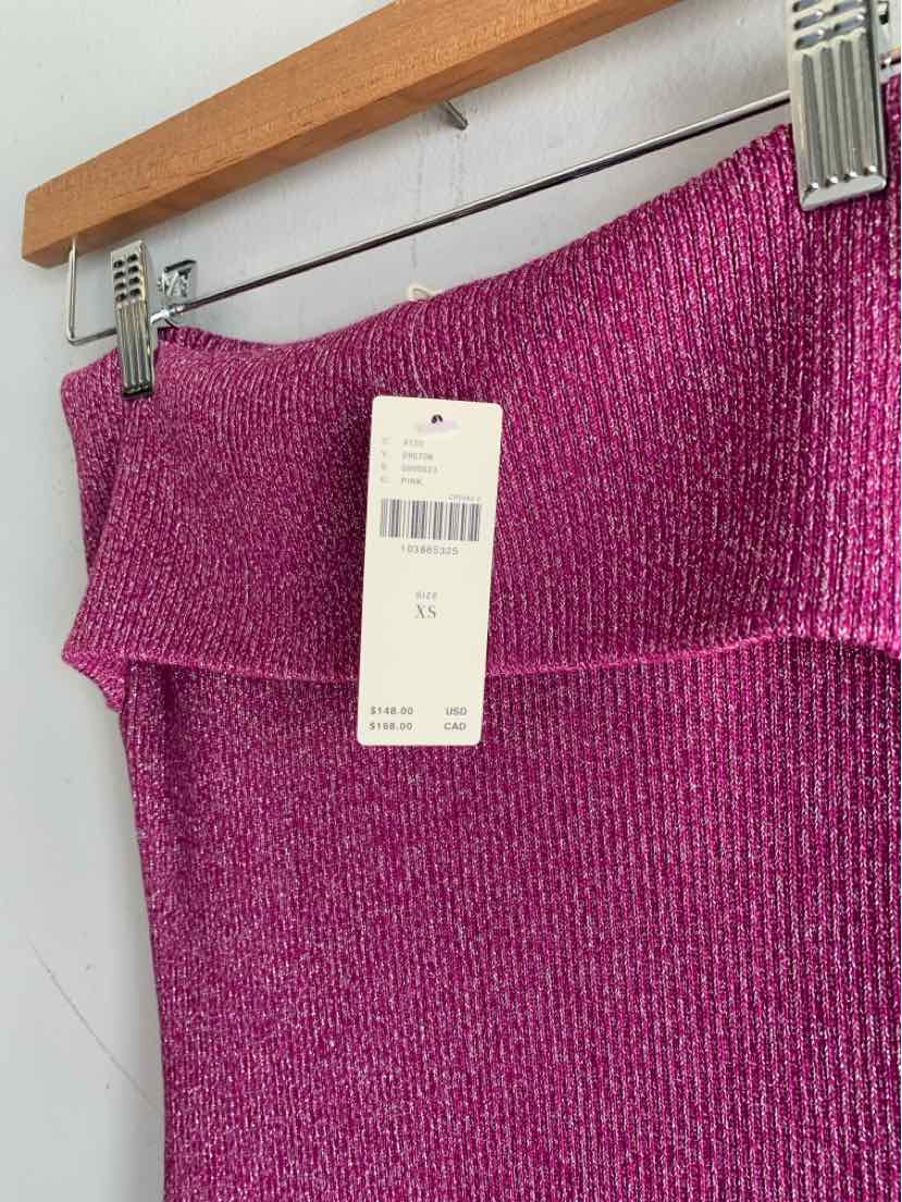 Folded ribbed knit skirt in vibrant magenta with attached white price tag on wooden hanger.