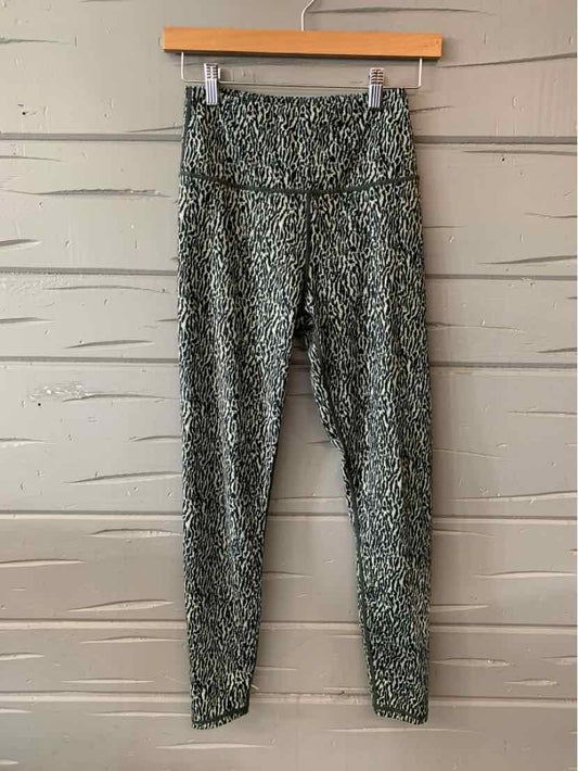Green cheetah print leggings with high waist and slim fit displayed on wooden hanger.