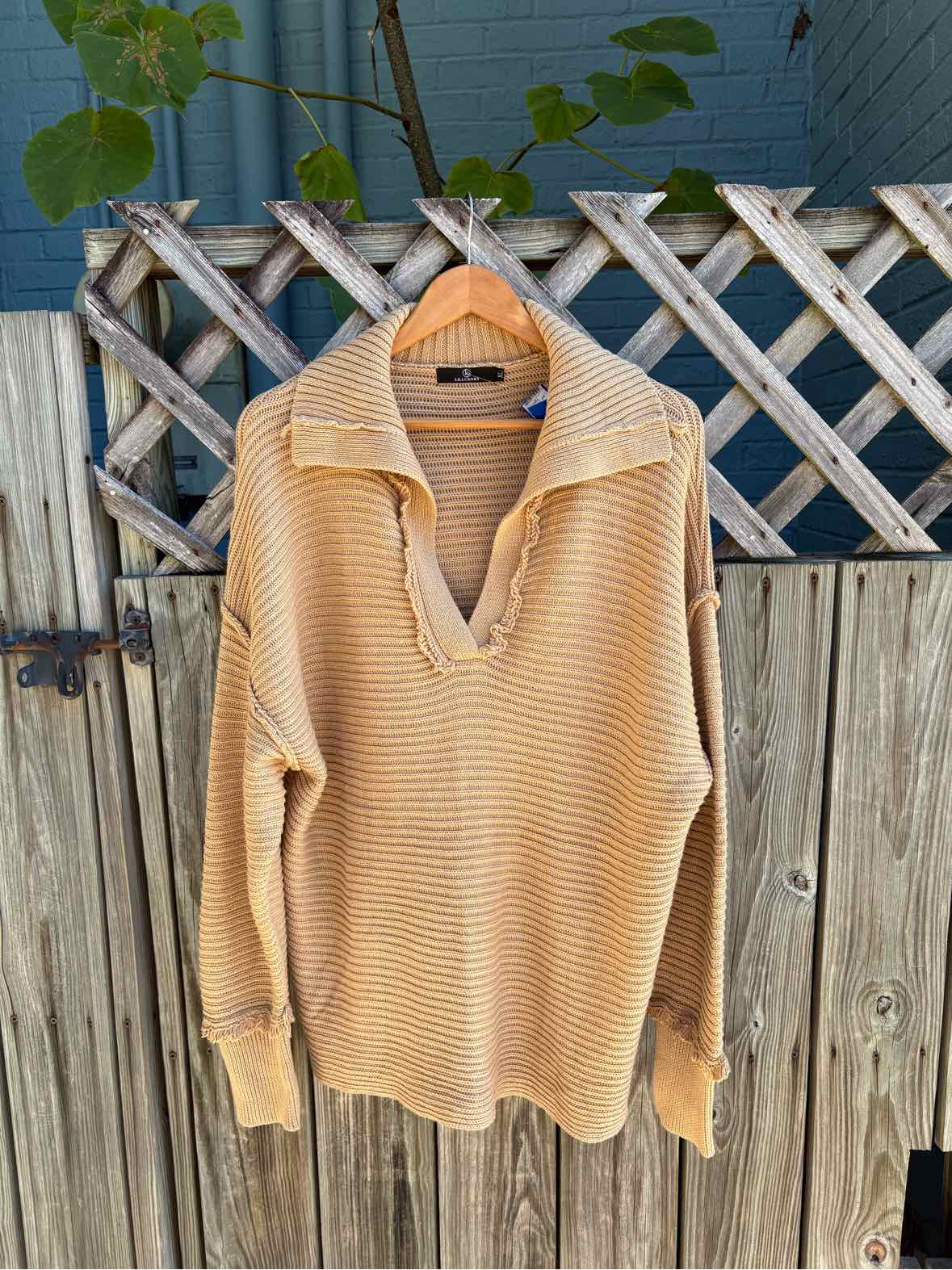 Tan ribbed knit sweater with a wide folded collar, V-neck, long sleeves, and a relaxed fit.