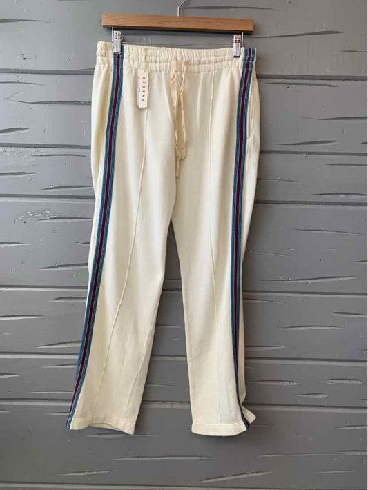 Cream casual pants with elastic waistband and multicolor side stripes hanging on wooden hanger.