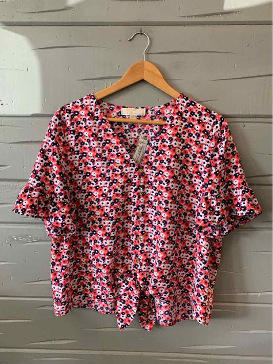 Pink floral short-sleeve blouse with V-neck and relaxed XL fit on wooden hanger.