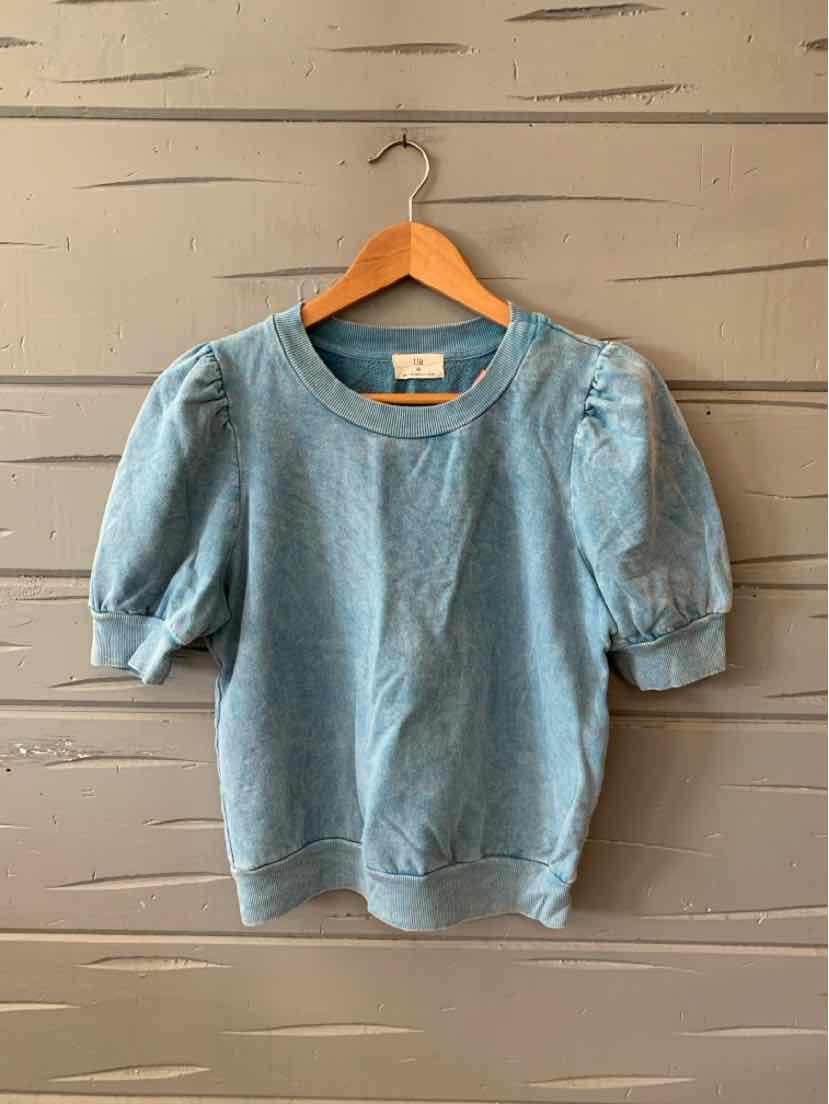 Light blue short-sleeve top with puffed sleeves and ribbed hem on wooden hanger.