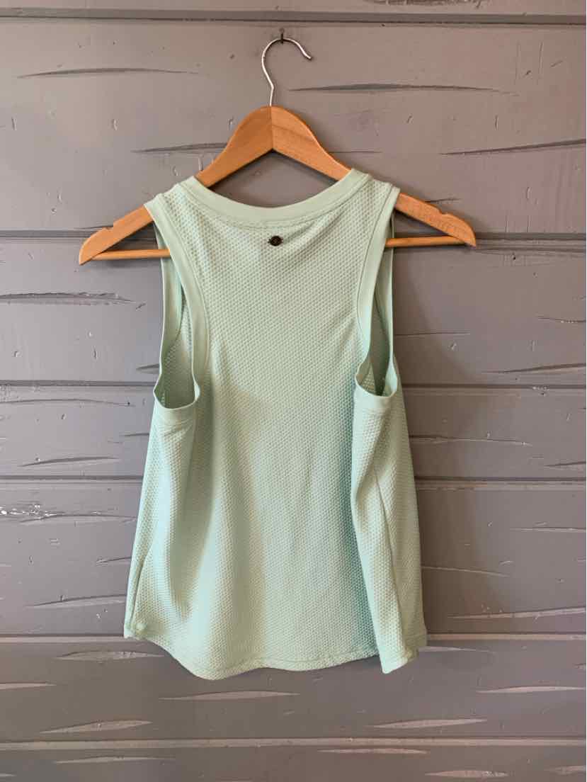 Light green sleeveless tank top with scoop neckline on wooden hanger against gray wooden wall.