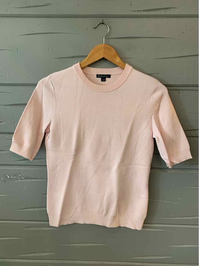 Light pink short-sleeve knit top with crew neck, slim fit, hanging on wooden hanger.