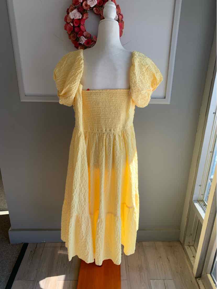 Yellow tiered dress with puff sleeves and square neckline on mannequin.