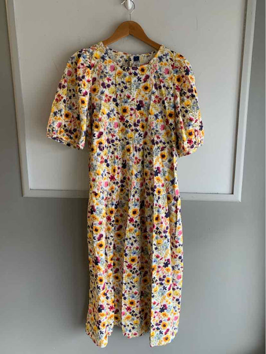 Yellow midi dress with colorful floral print and short puff sleeves on wooden hanger.