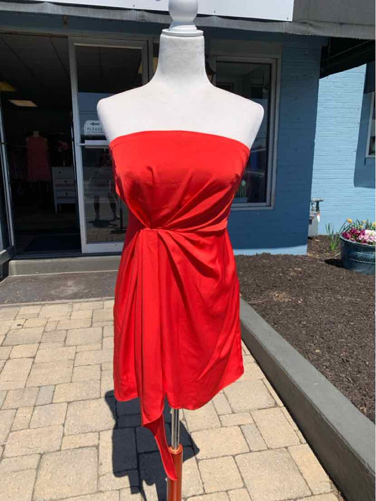 Strapless red mini dress with ruched detailing and side tie on mannequin outdoors.