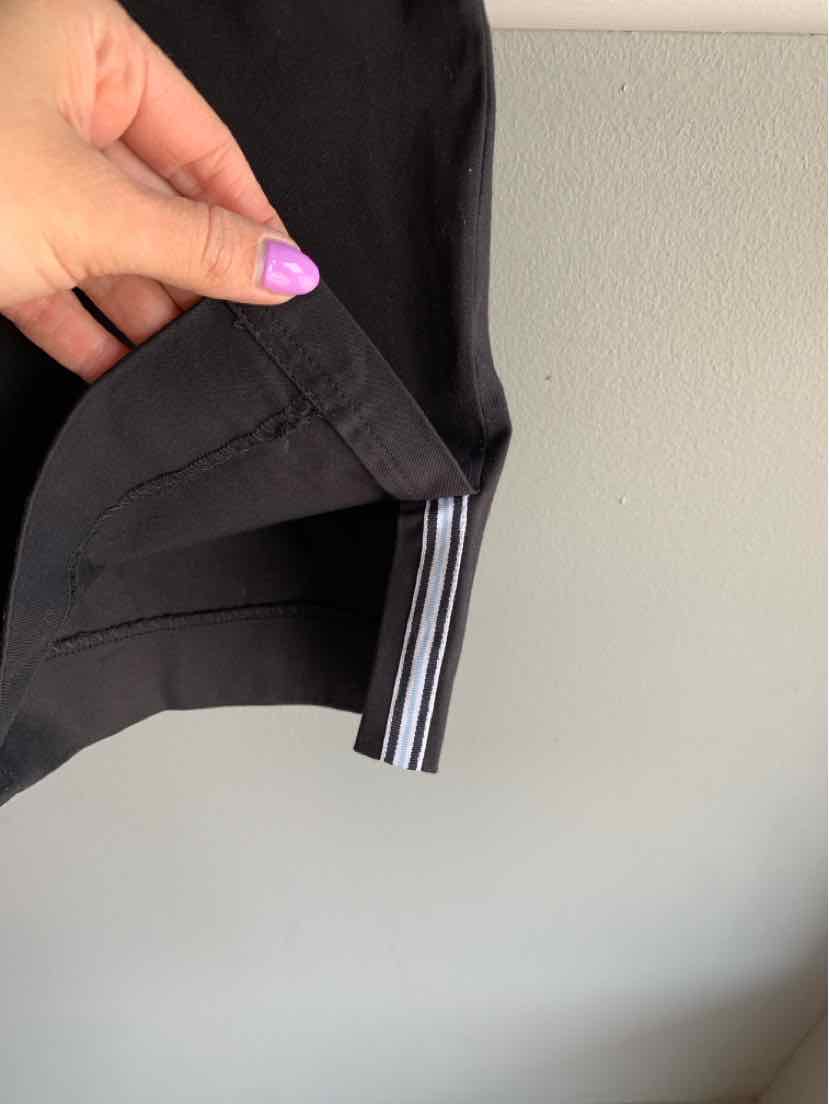 Black tapered pants with striped inner cuff detail, size 14W, held by hand with purple nail polish.