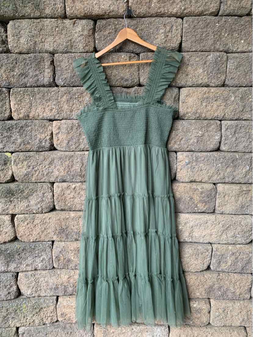 Green sleeveless midi dress with ruffled straps and tiered skirt on wooden hanger.