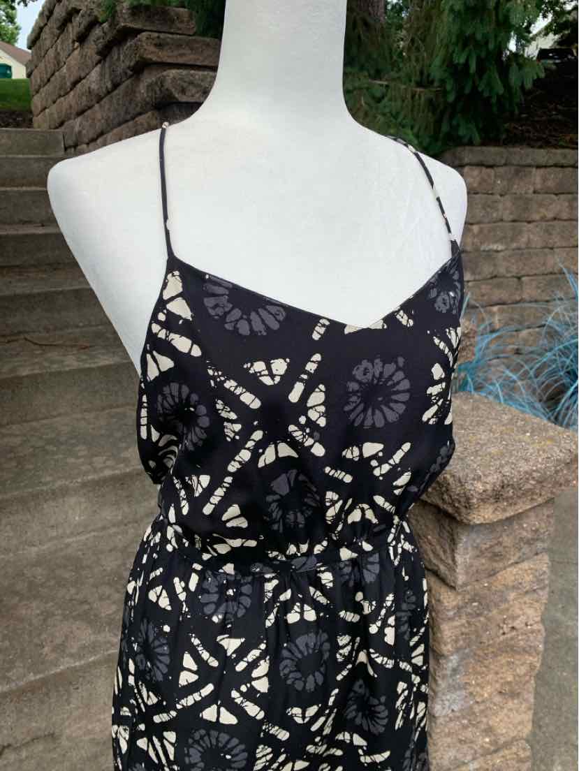 Black sleeveless dress with white geometric floral pattern and thin spaghetti straps.