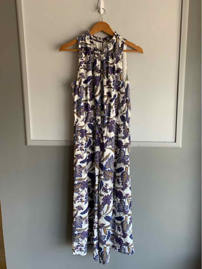 Sleeveless blue and white floral maxi dress with a loose fit and tie waist hanging on wooden hanger.