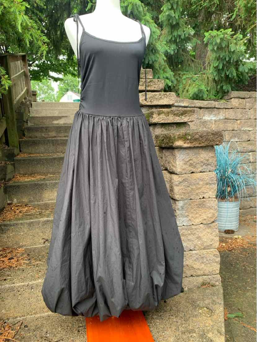 Black sleeveless dress with a fitted bodice and voluminous balloon skirt on a mannequin outdoors.