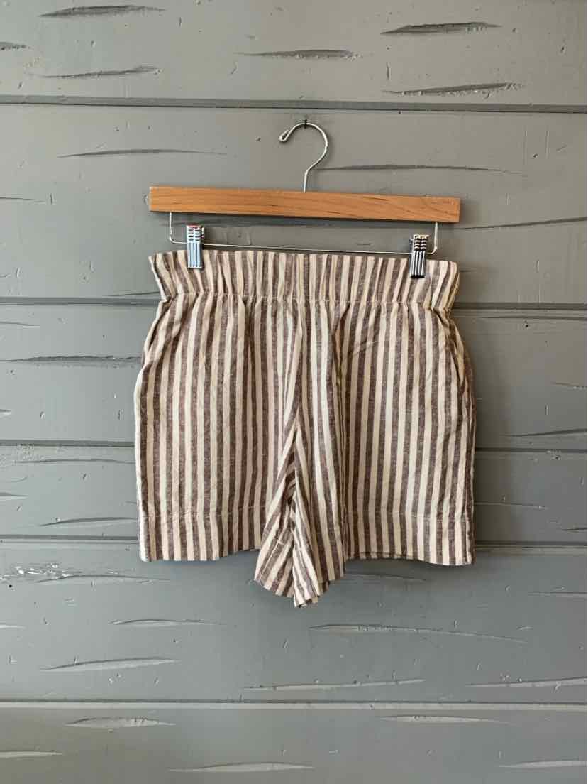 Beige and white vertical striped casual shorts with elastic waistband hanging on wooden hanger.